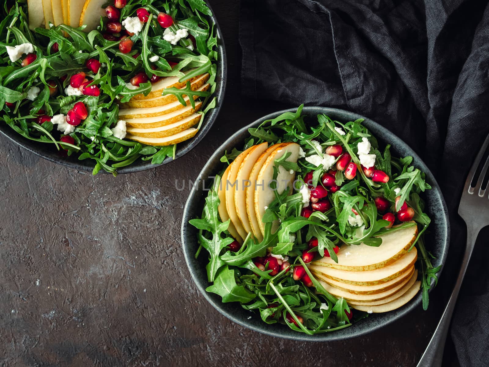 Vegan salad bowl with arugula, pear, pomegranate, cheese by fascinadora