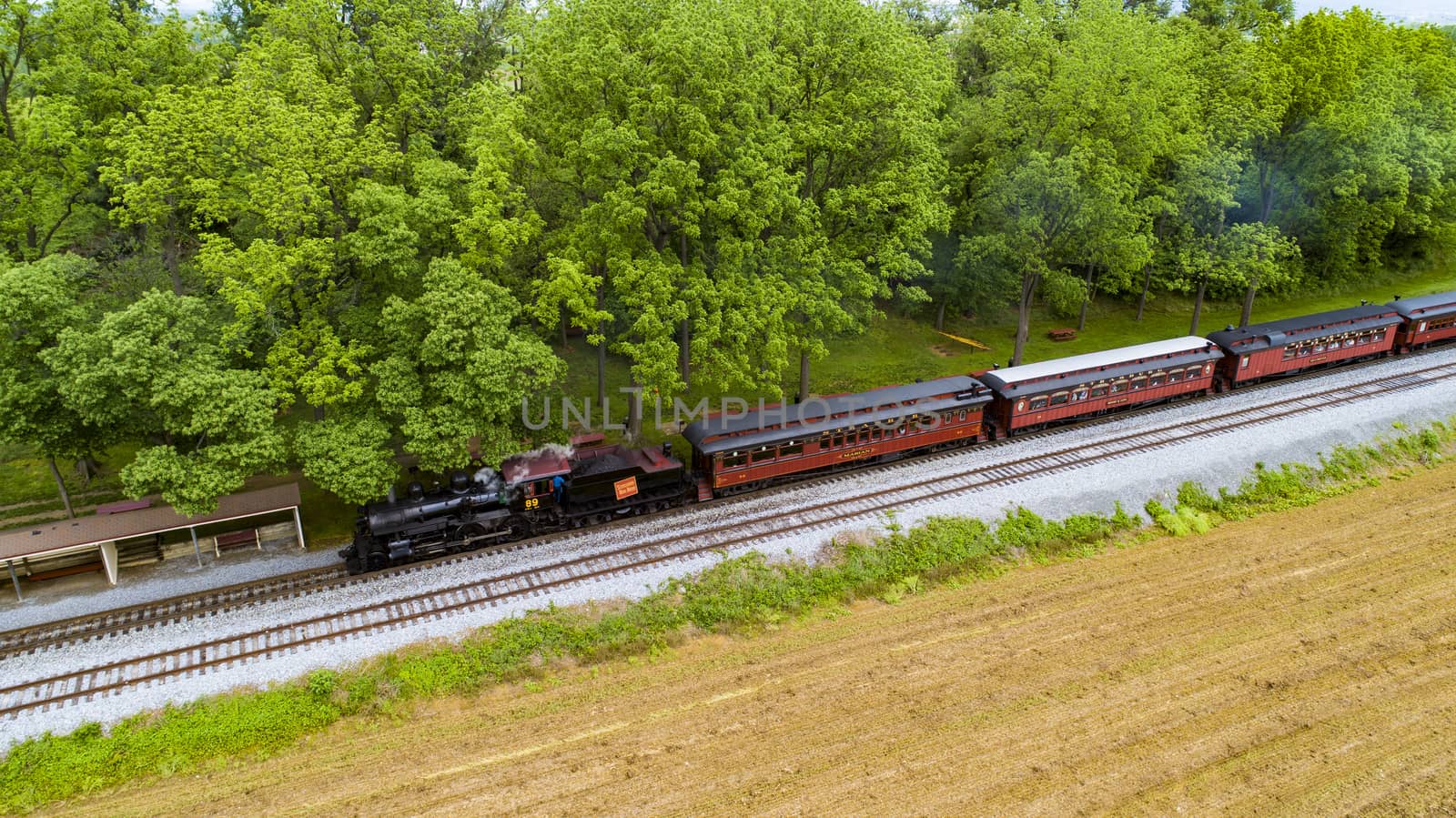 Ariel View of a Steam Passenger Train Pulling into Picnic Area Blowing Smoke on a Sunny Summer Day as seen by a Drone