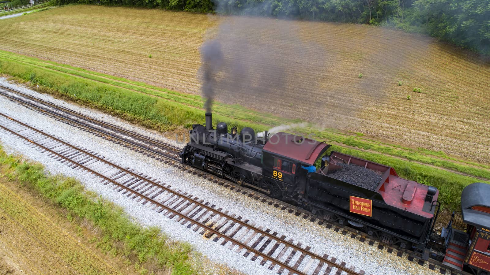 Ariel View of a Steam Passenger Train Pulling into Picnic Area Blowing Smoke on a Sunny Summer Day as seen by a Drone