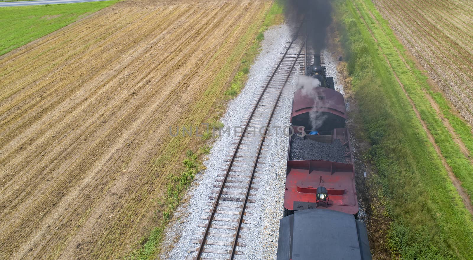 Ariel View of a Steam Passenger Train Pulling into Picnic Area Blowing Smoke on a Sunny Summer Day as seen by a Drone
