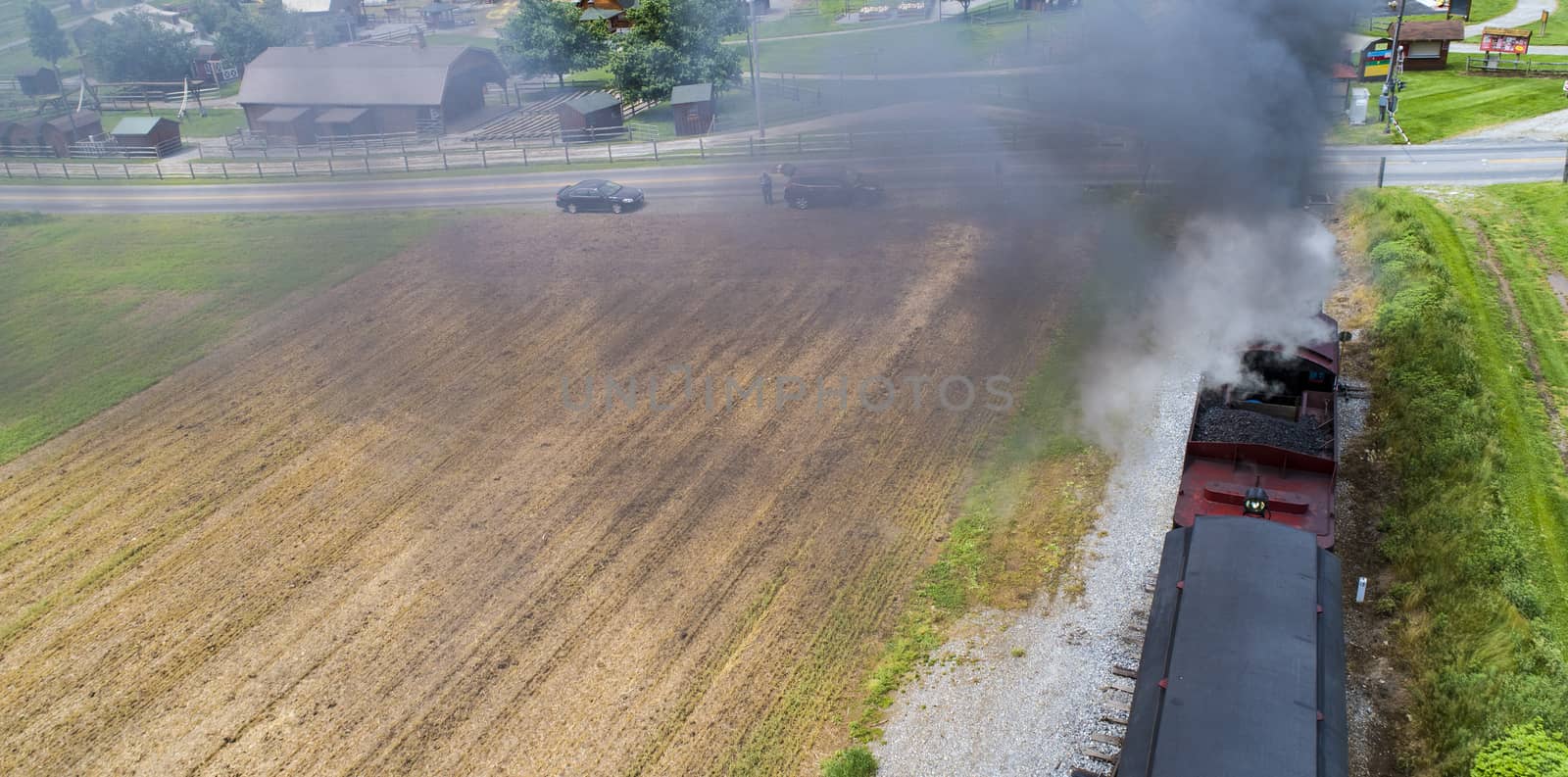 Ariel View of a Steam Passenger Train Pulling into Picnic Area Blowing Smoke on a Sunny Summer Day as seen by a Drone