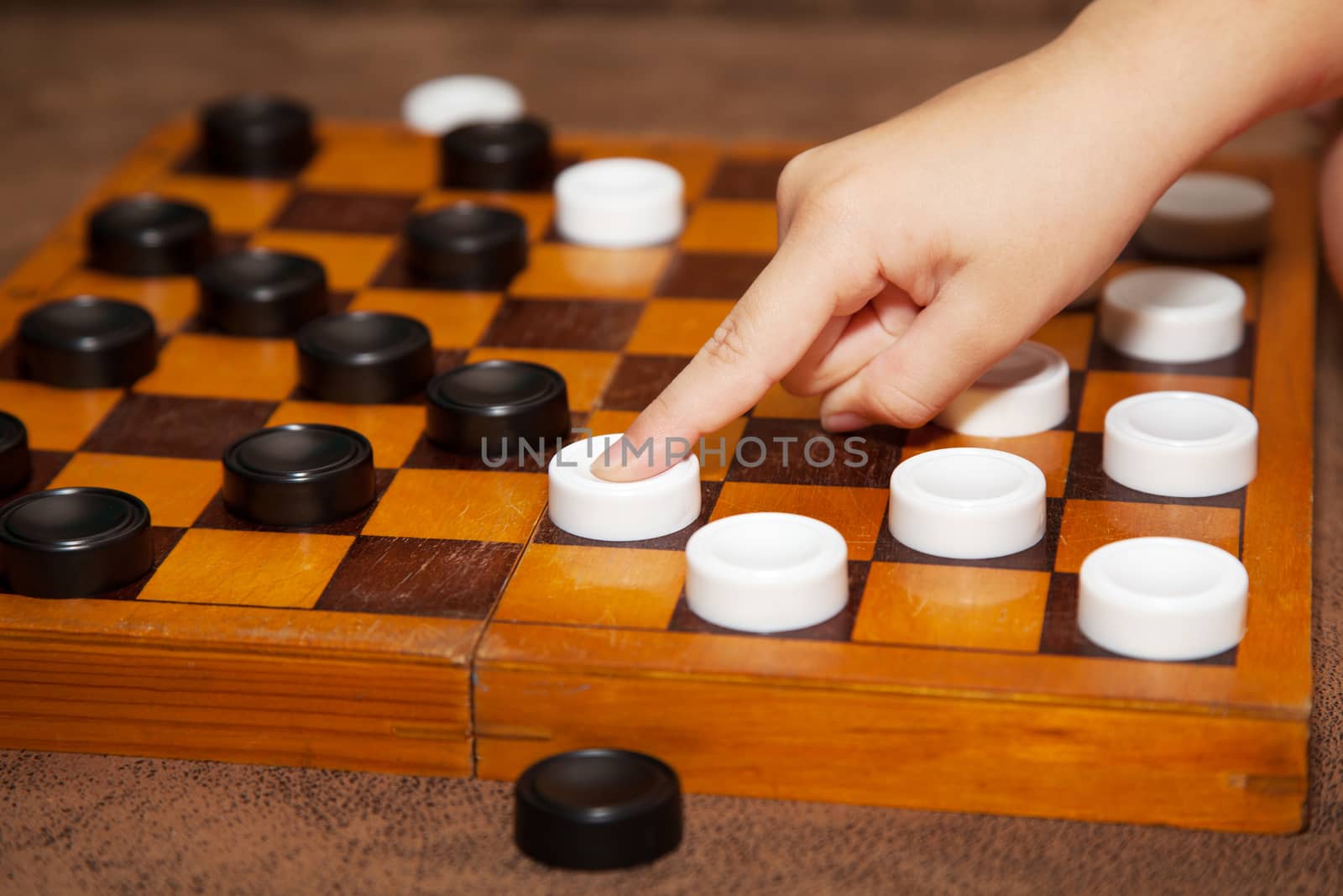 child's hand moves the white piece to the chessboard