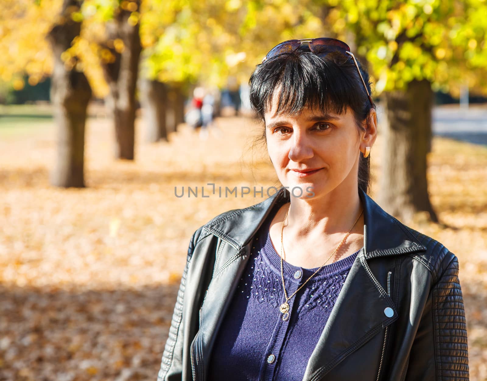 young brunette smiling woman on a walk in the park on sunny autumn day