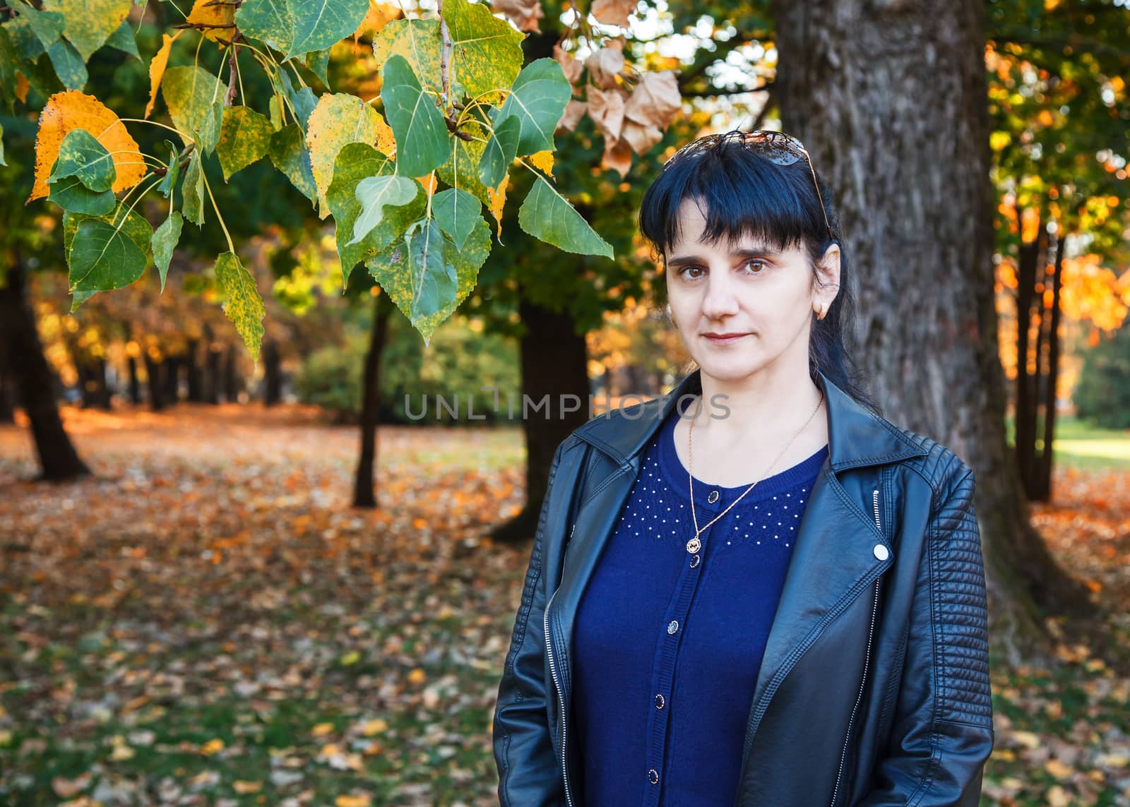 young brunette smiling woman on a walk in the park on sunny autumn day