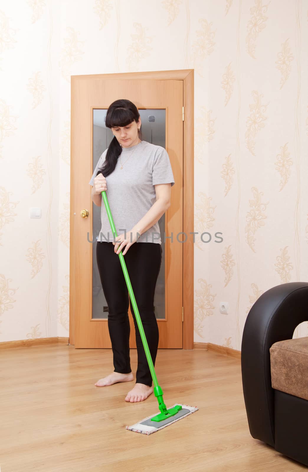 woman washes wooden floor with a mop by raddnatt