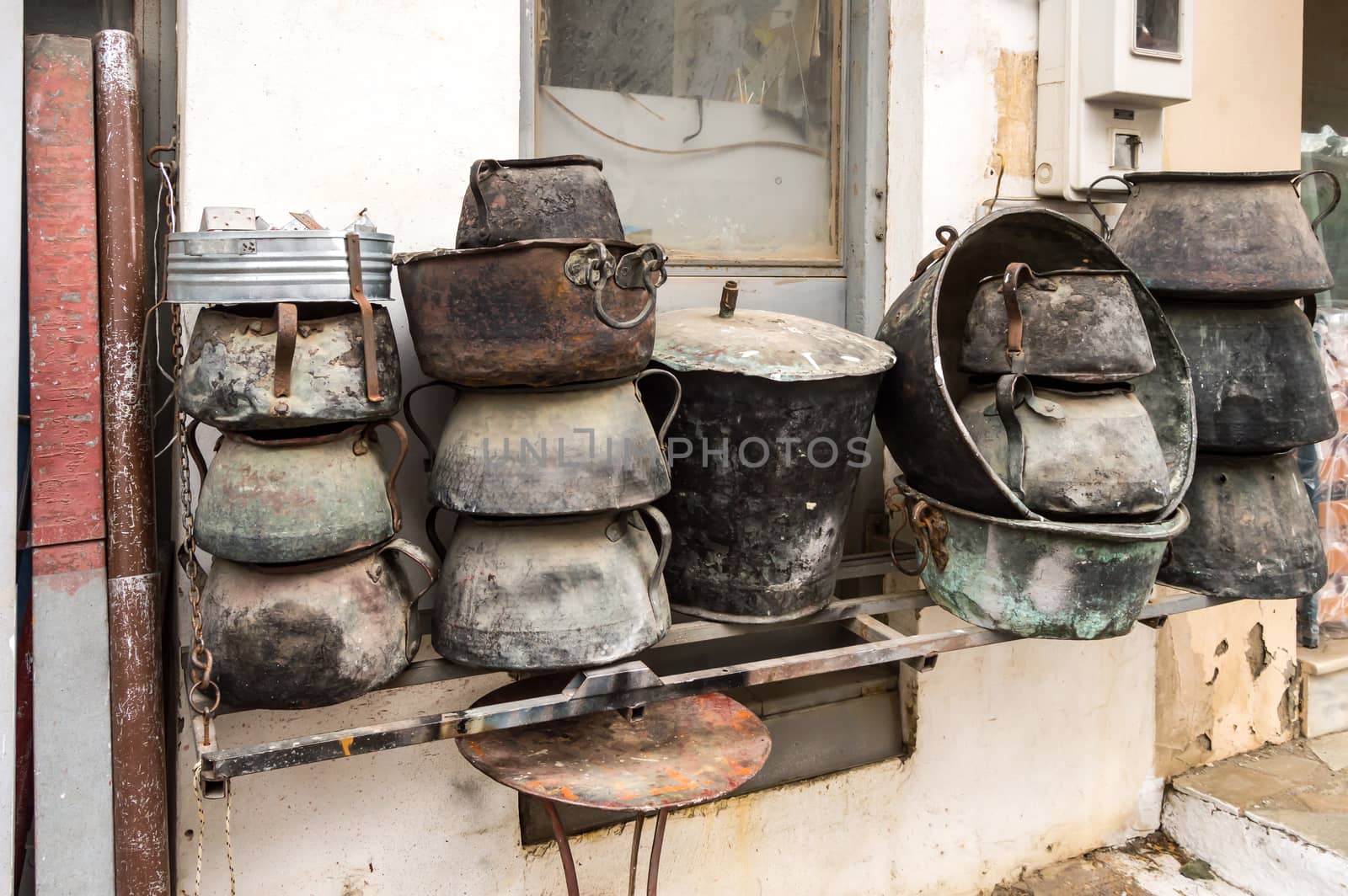 Several old cauldrons in heap in front of a facade