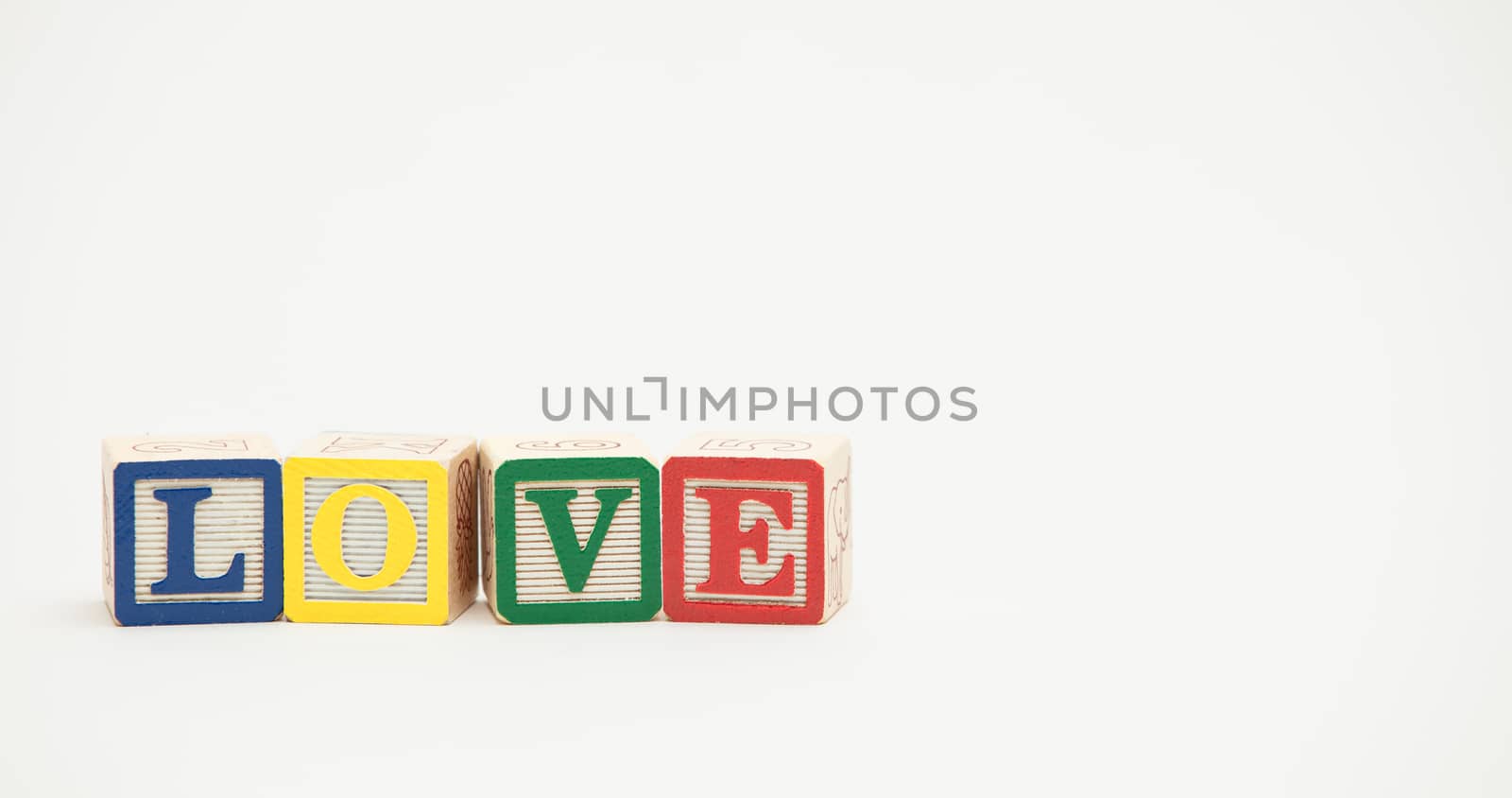 Small wooden toy blocks spell out the word love in colorful letters on a white background.