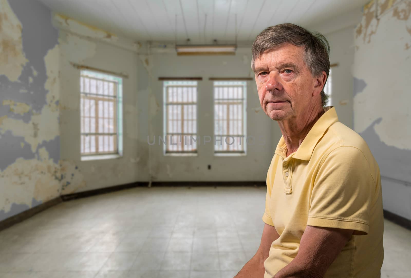 Senior old man looking at camera with a background of an old tenement apartment with peeling paint on walls
