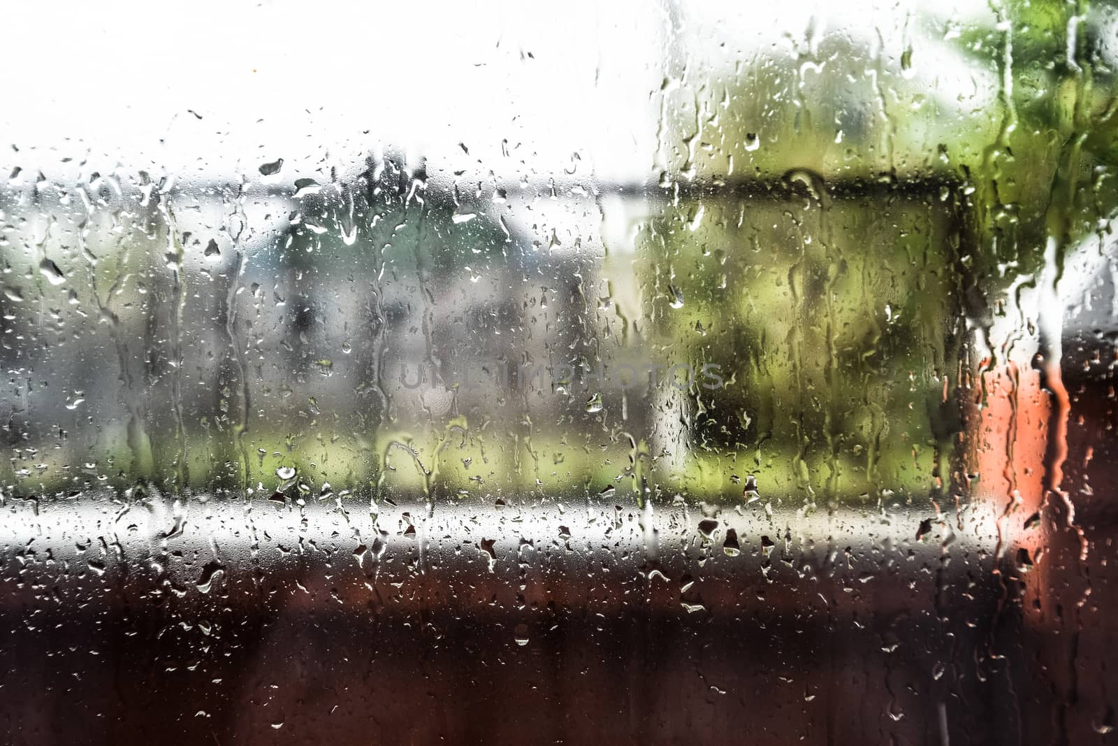 Raindrops on the window pane. Blurred background outside the window in the rain.