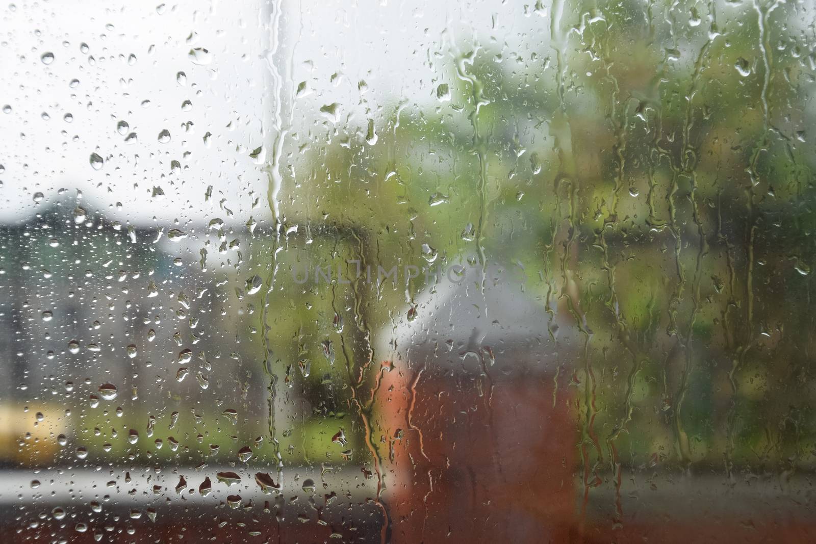 Raindrops on the window pane. Blurred background outside the window in the rain.