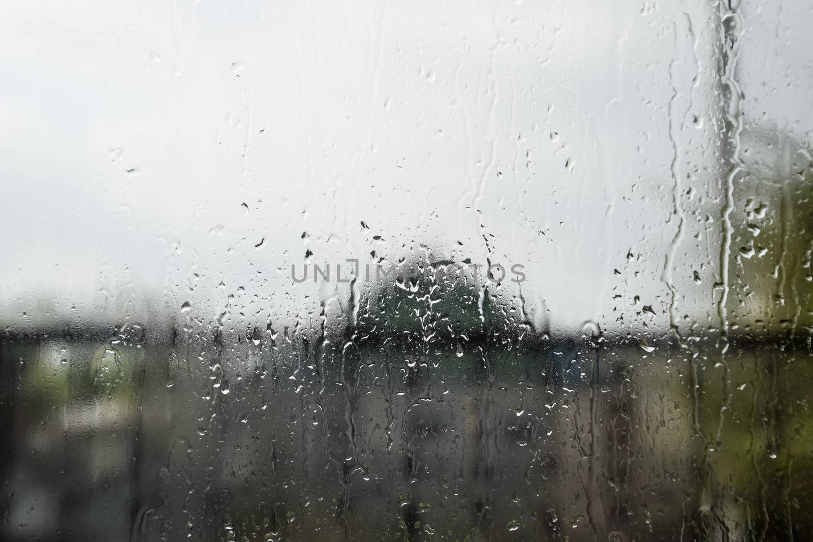Raindrops on the window pane. Blurred background outside the window in the rain.