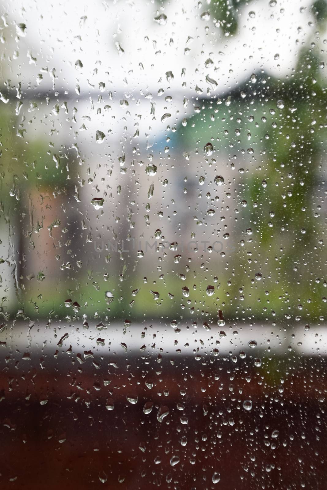 Raindrops on the window pane. Blurred background outside the window in the rain.