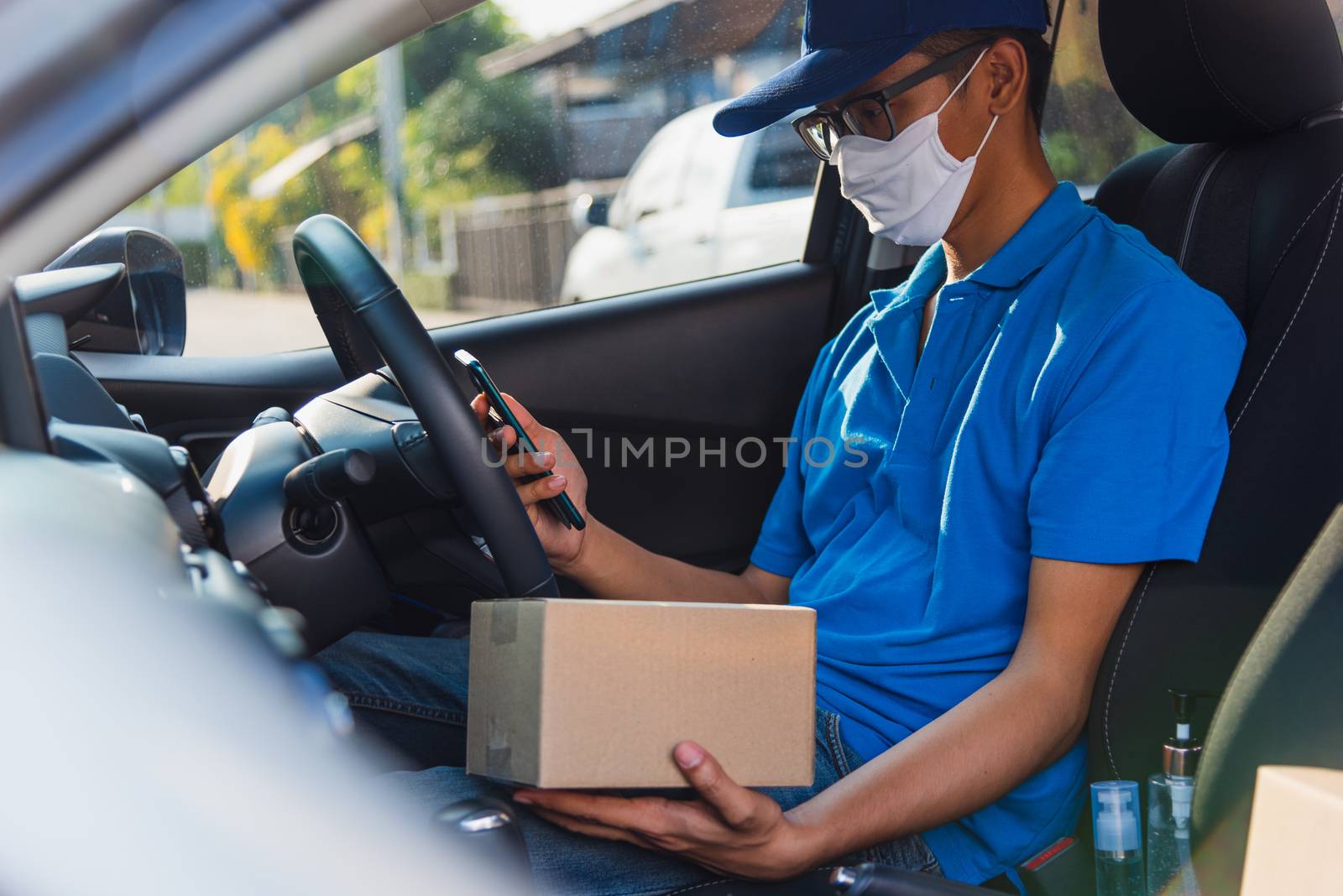 delivery man courier holding deliveries out boxes and using mobi by Sorapop