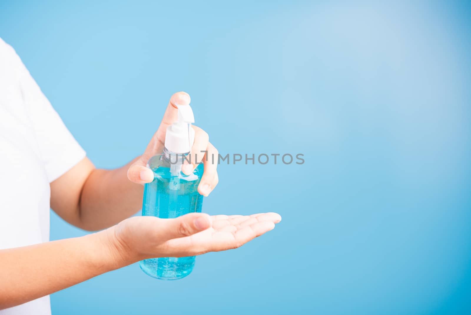 Closeup Hand Asian young woman applying pump dispenser sanitizer alcohol gel on hand wash cleaning, hygiene prevention COVID-19 or coronavirus protection concept, isolated on blue background