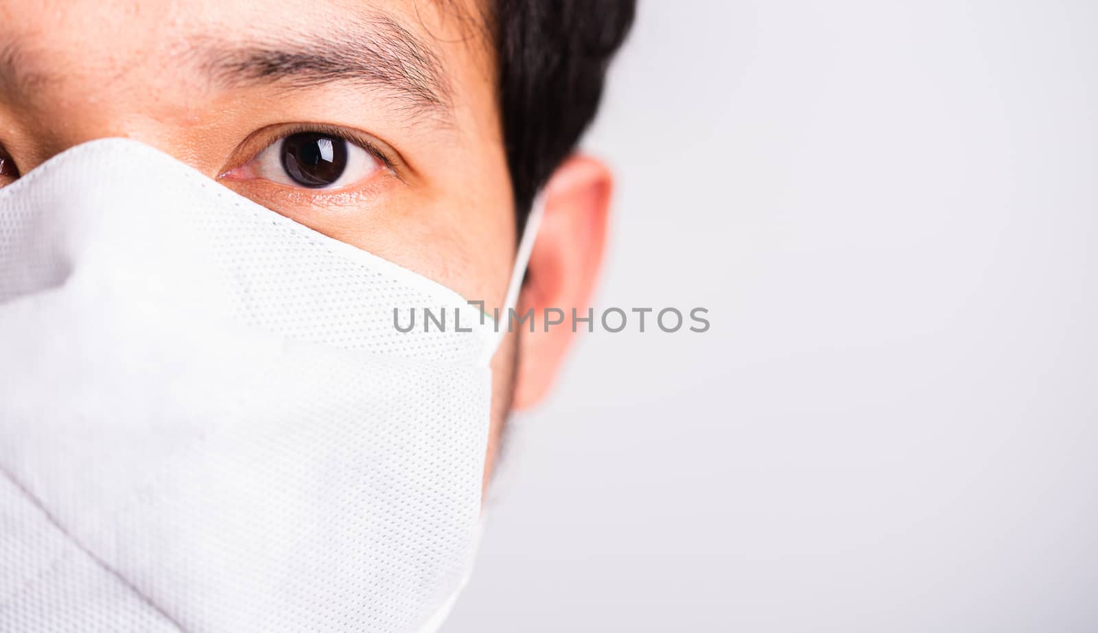 Closeup Asian handsome Man wearing surgical hygienic protective cloth face mask against coronavirus, studio shot isolated white background, COVID-19 medical concept