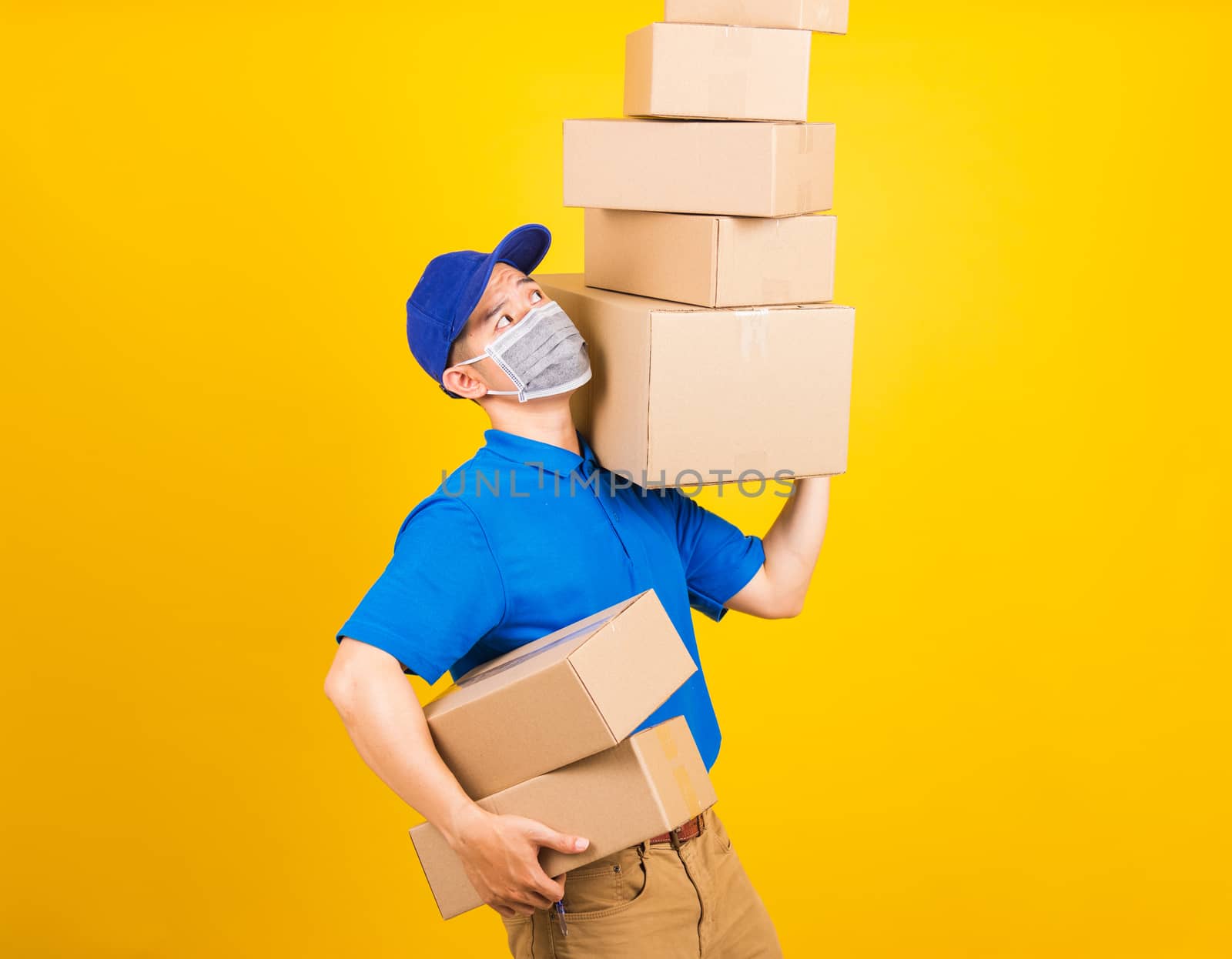 delivery worker man wearing face mask protective lifting stack a by Sorapop