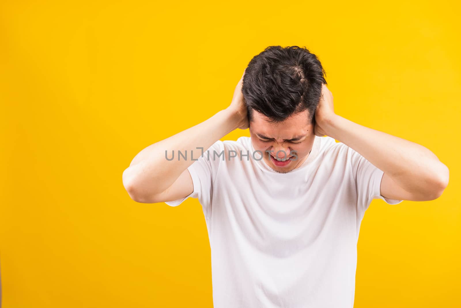 young man standing he covering his ears with hands and shouting  by Sorapop