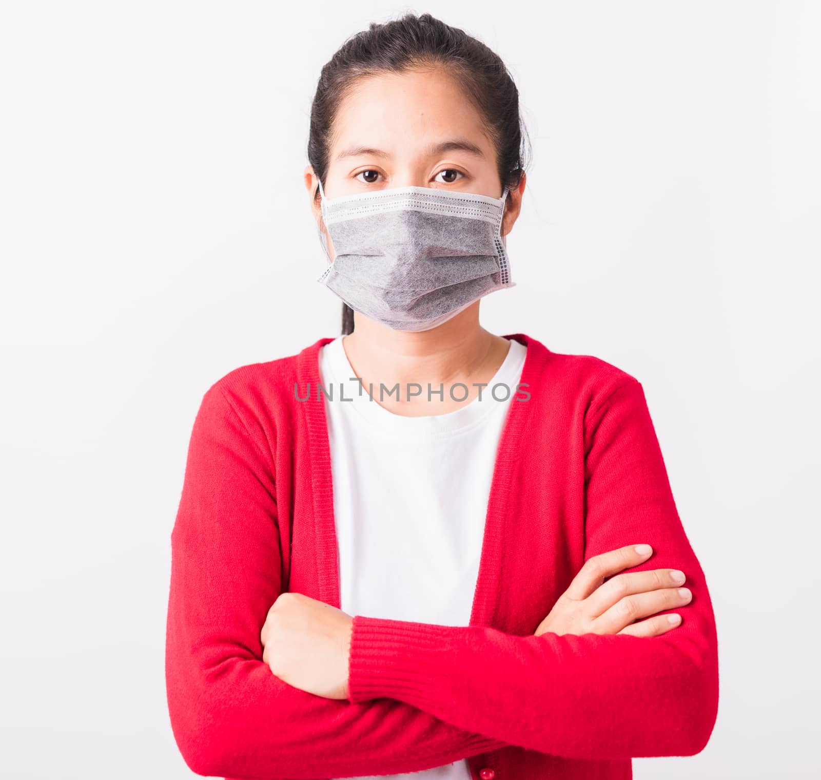 Asian adult woman stand crossed arm wearing red shirt and face mask protective against coronavirus or COVID-19 virus or filter dust pm2.5 and air pollution, studio shot isolated white background