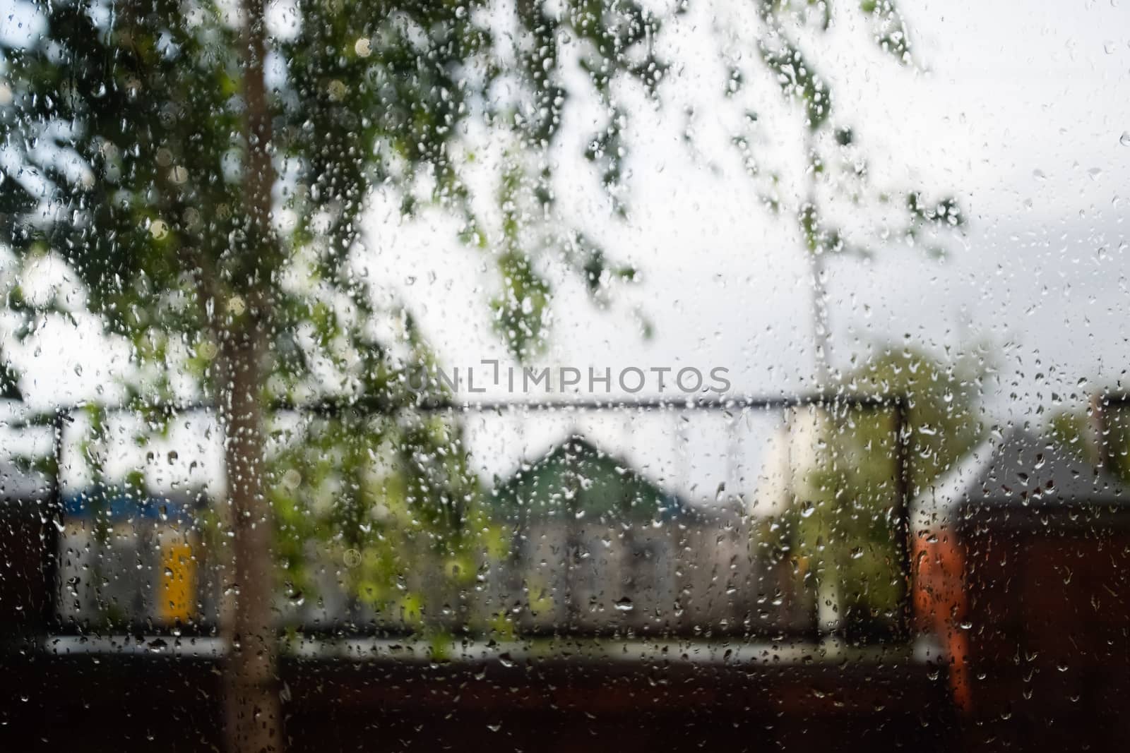 Raindrops on window pane. Blurred background outside the window in the rain. by fedoseevaolga