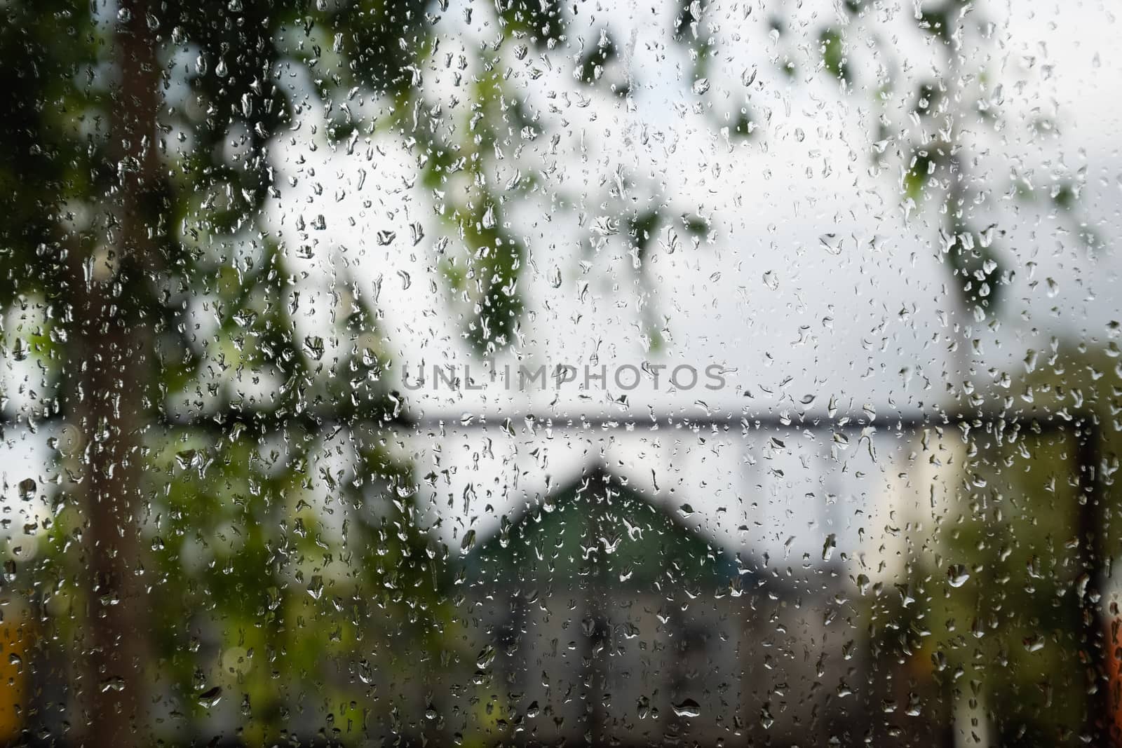Raindrops on the window pane. Blurred background outside the window in the rain.