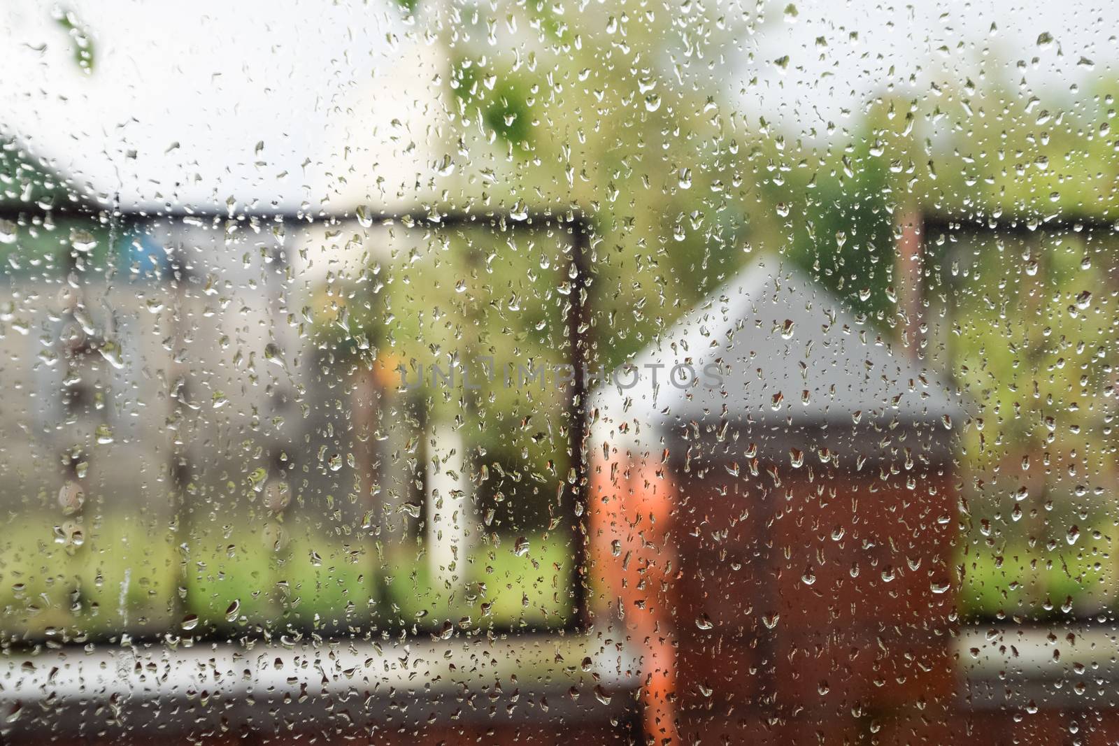 Raindrops on the window pane. Blurred background outside the window in the rain.