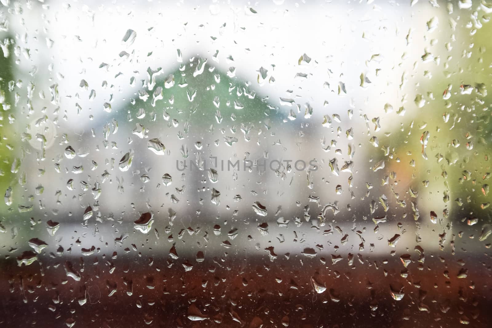 Raindrops on the window pane. Blurred background outside the window in the rain.