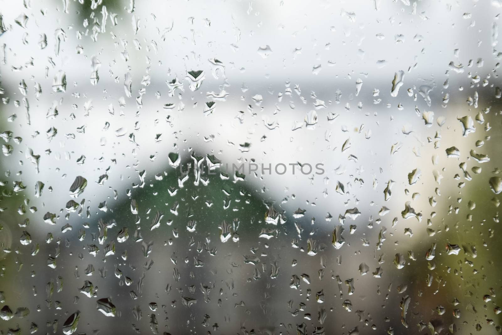 Raindrops on the window pane. Blurred background outside the window in the rain.