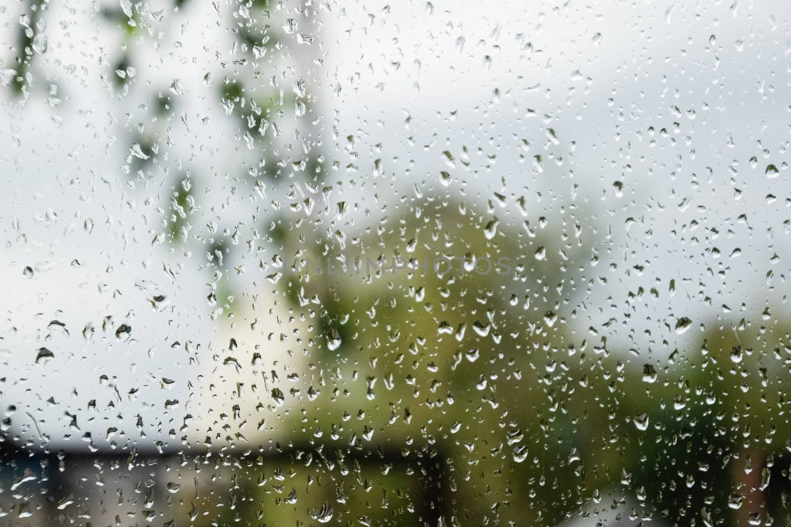 Raindrops on the window pane. Blurred background outside the window in the rain.