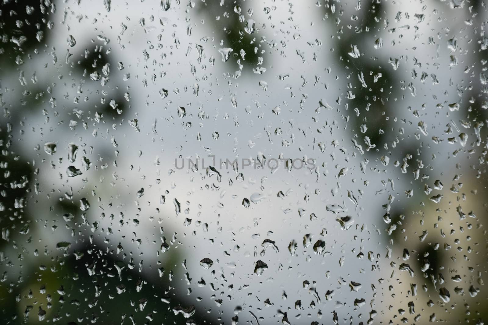 Raindrops on the window pane. Blurred background outside the window in the rain.