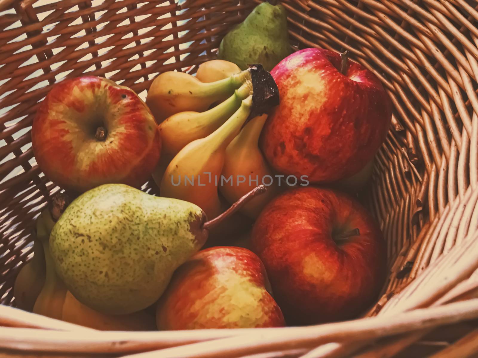 Organic apples, pears and bananas on rustic in a wicker basket, fruits farming and agriculture