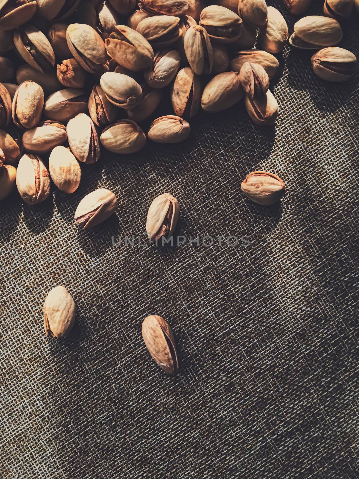 Pistachio nuts on rustic linen background, food and nutrition