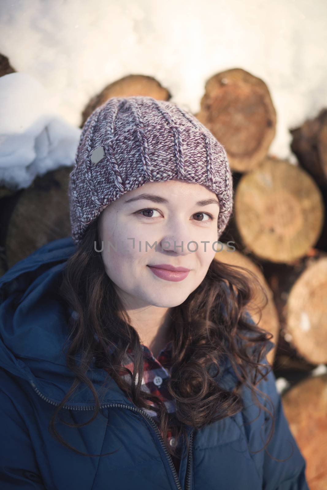 the beautiful young girl in a warm cap from wool of the alpaca in the winter forest by polyats