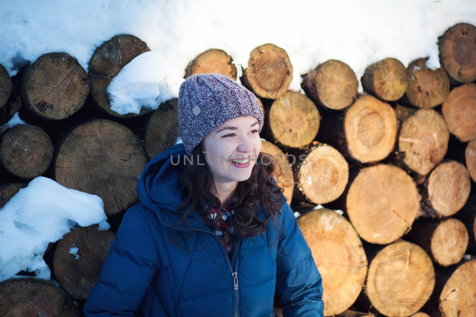 the beautiful young girl in a warm cap from wool of the alpaca in the winter forest. knitting