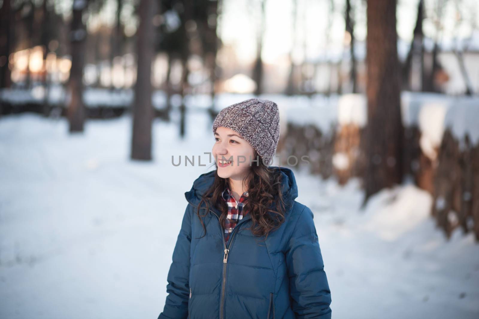 the beautiful young girl in a warm cap from wool of the alpaca in the winter forest. knitting
