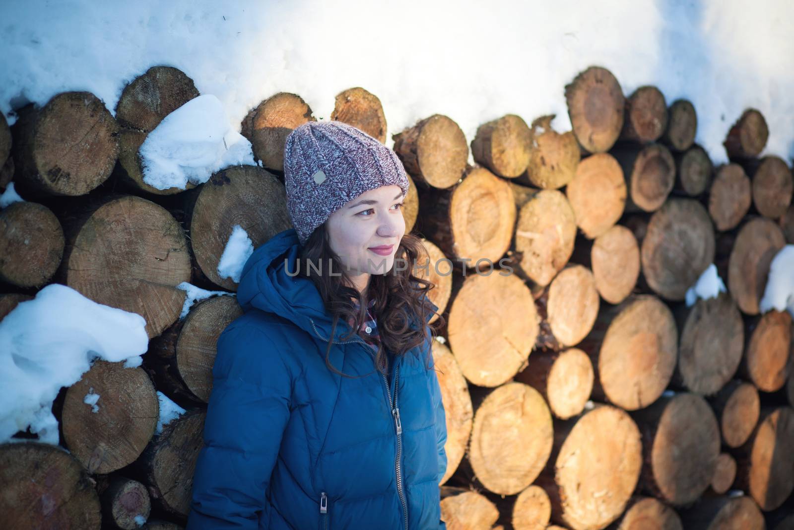 the beautiful young girl in a warm cap from wool of the alpaca in the winter forest. knitting