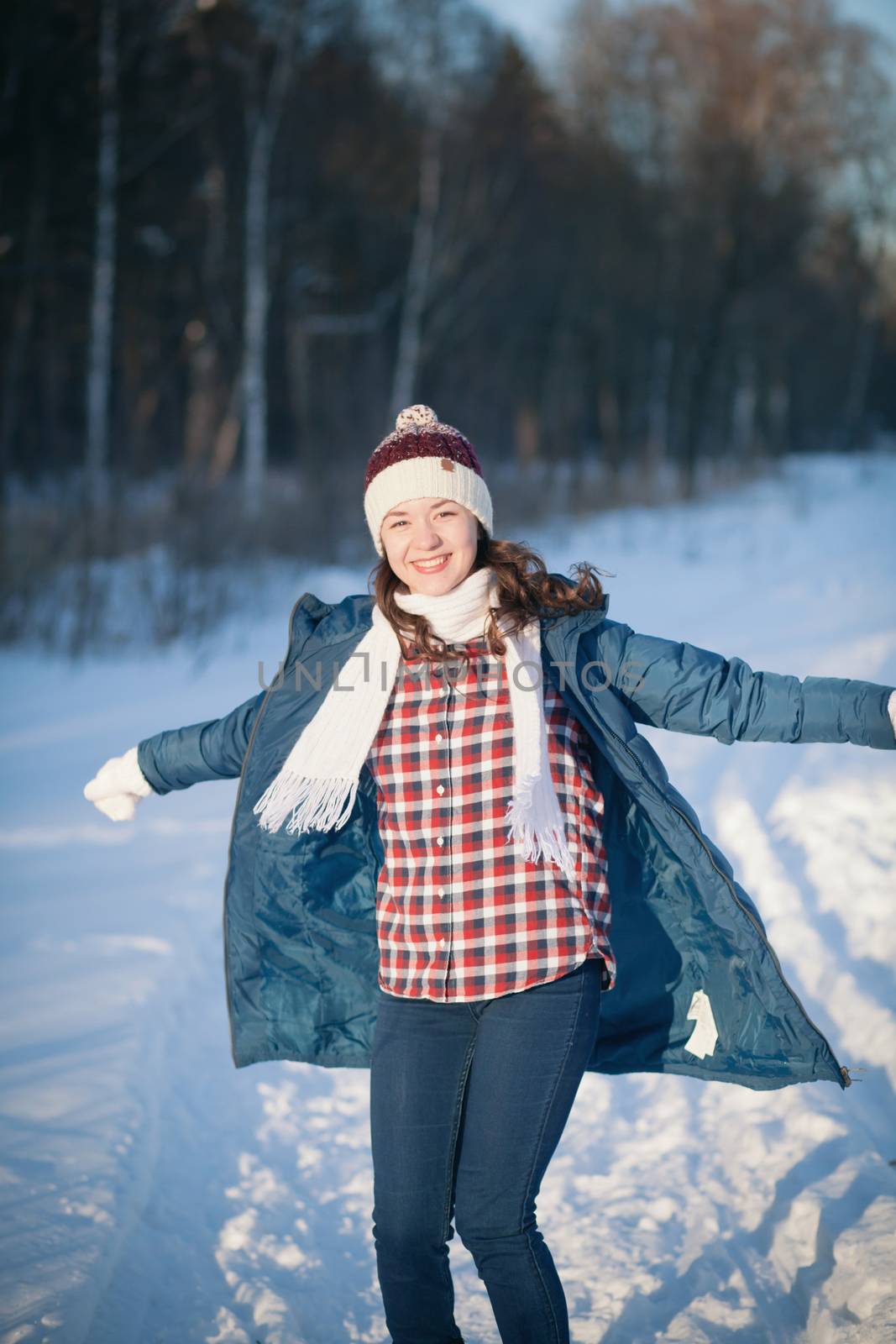 the beautiful young girl in a warm cap from wool of the alpaca in the winter forest. knitting