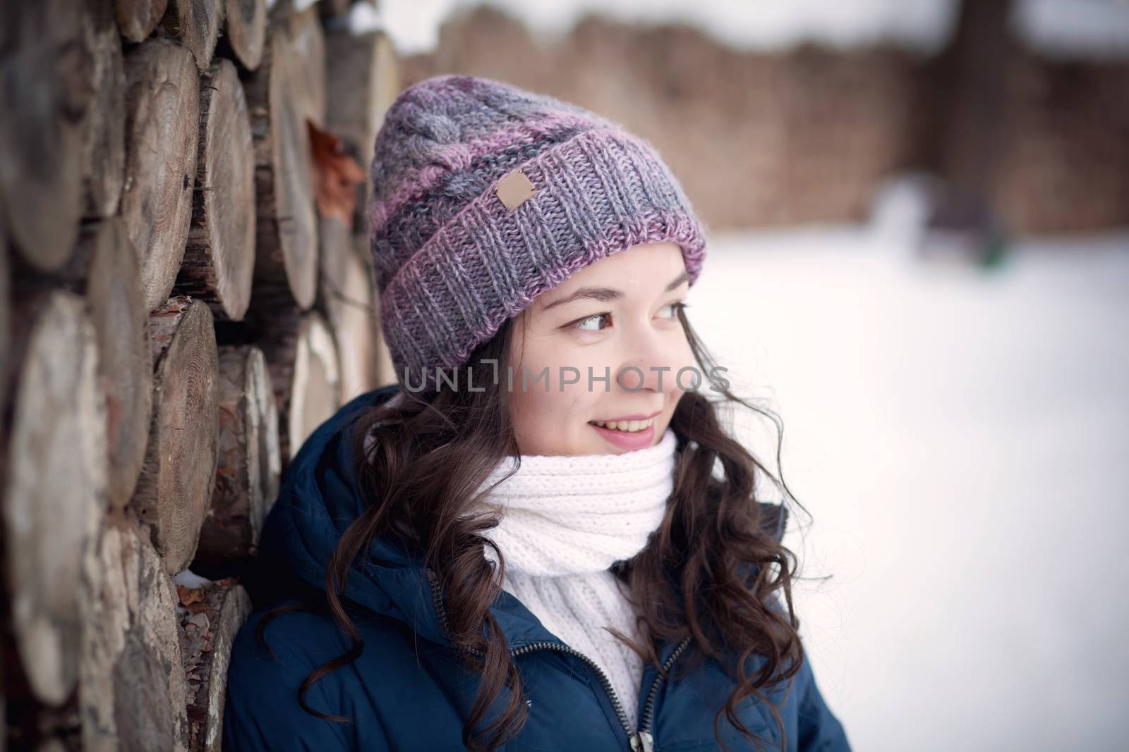 the beautiful young girl in a warm cap from wool of the alpaca in the winter forest. knitting