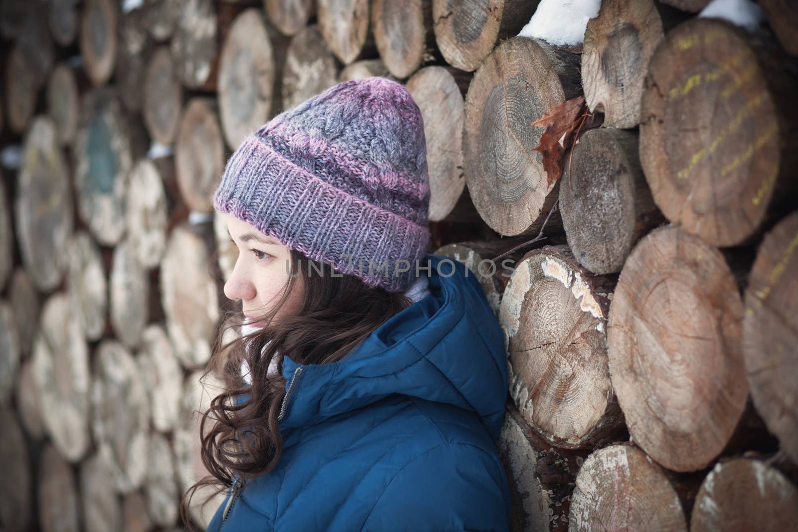 the beautiful young girl in a warm cap from wool of the alpaca in the winter forest. knitting