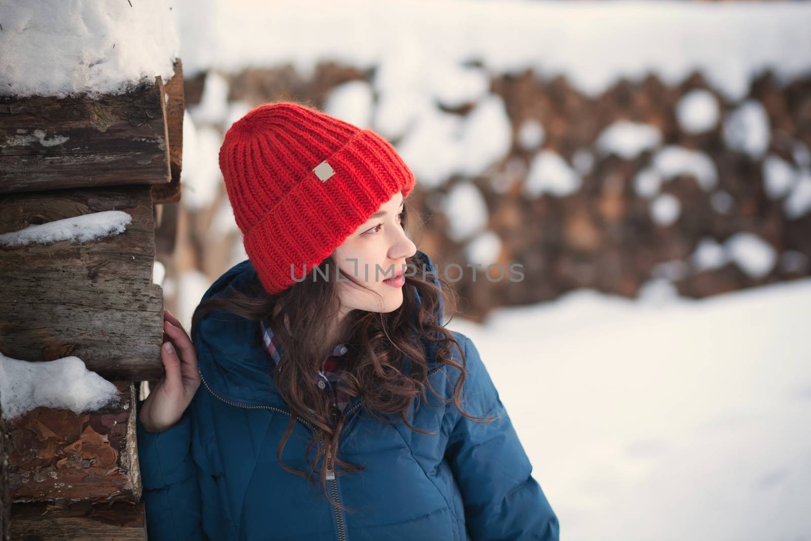 the beautiful young girl in a warm cap from wool of the alpaca in the winter forest. knitting
