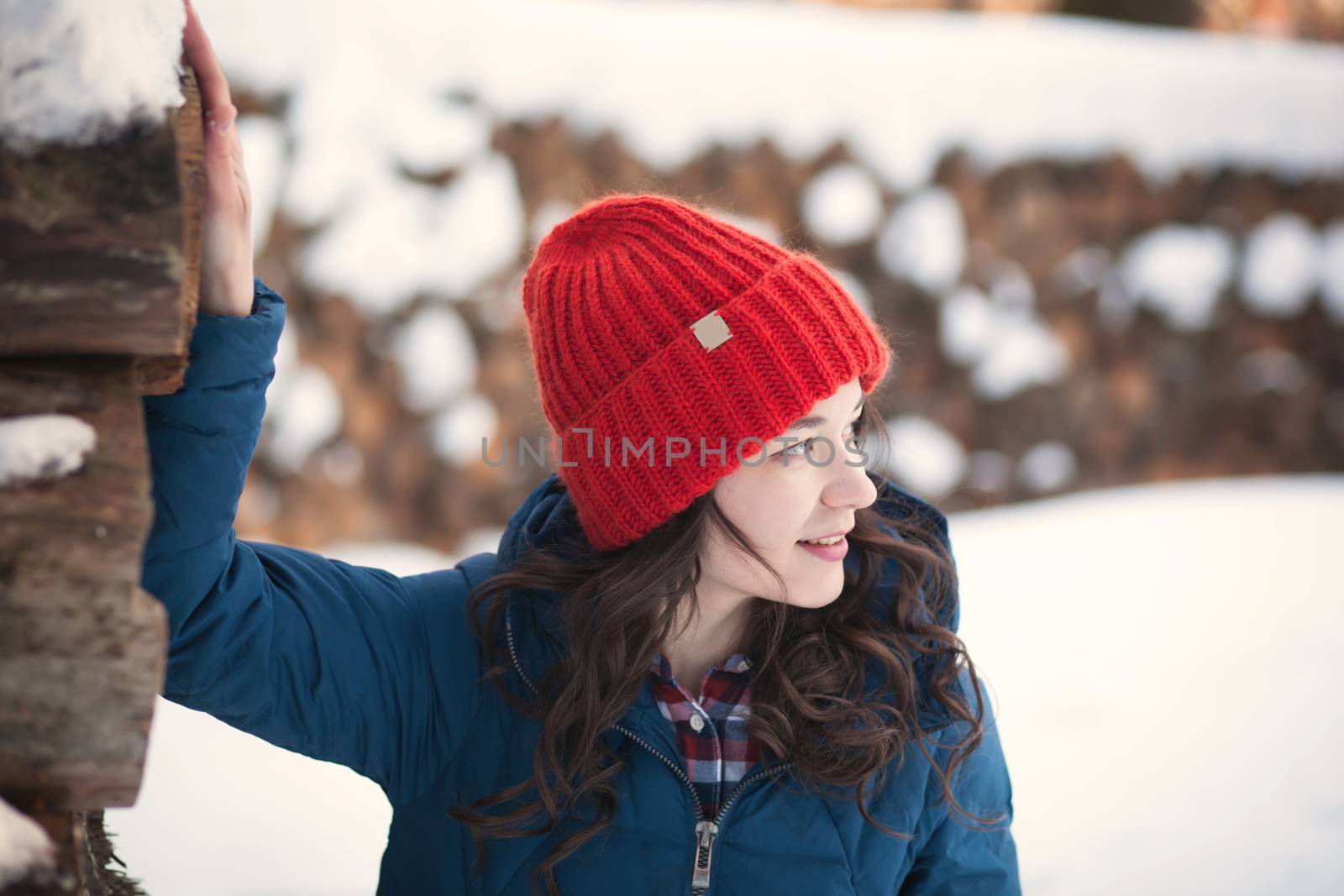 the beautiful young girl in a warm cap from wool of the alpaca in the winter forest. knitting