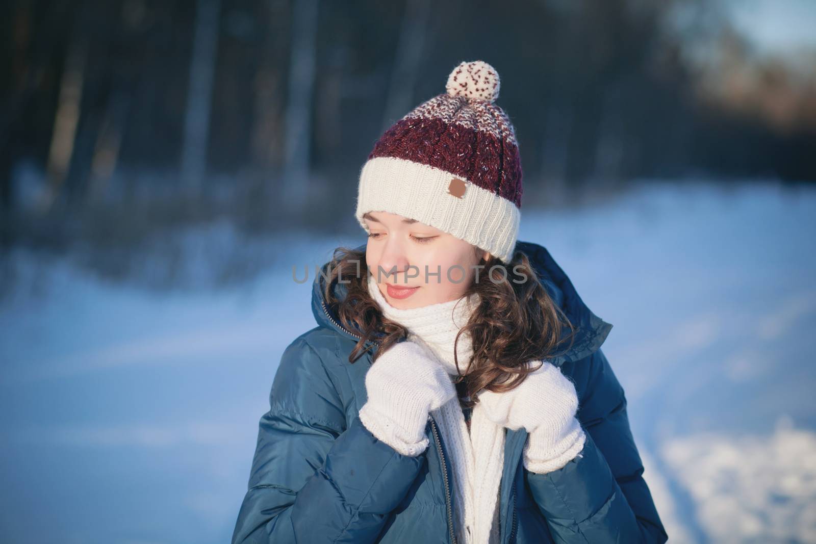 the beautiful young girl in a warm cap from wool of the alpaca in the winter forest by polyats