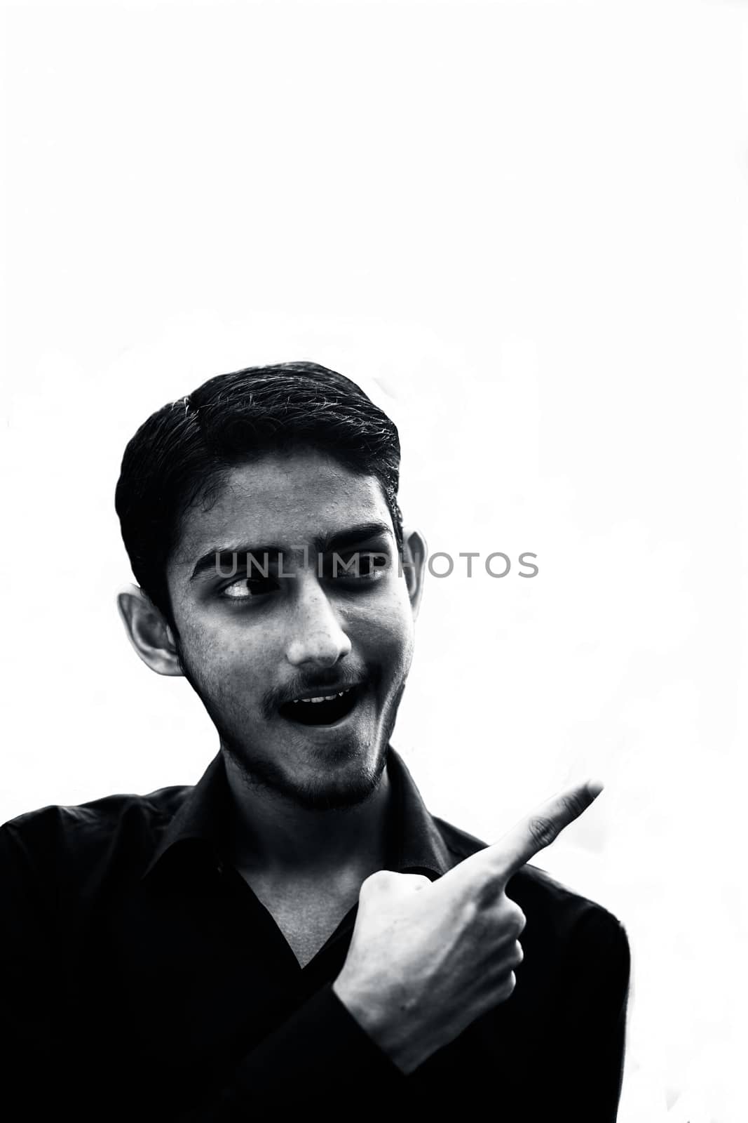 Close up of young Caucasian man with bear isolated opens mouth widely and stares at the camera while pointing towards the blank side. by mirzamlk