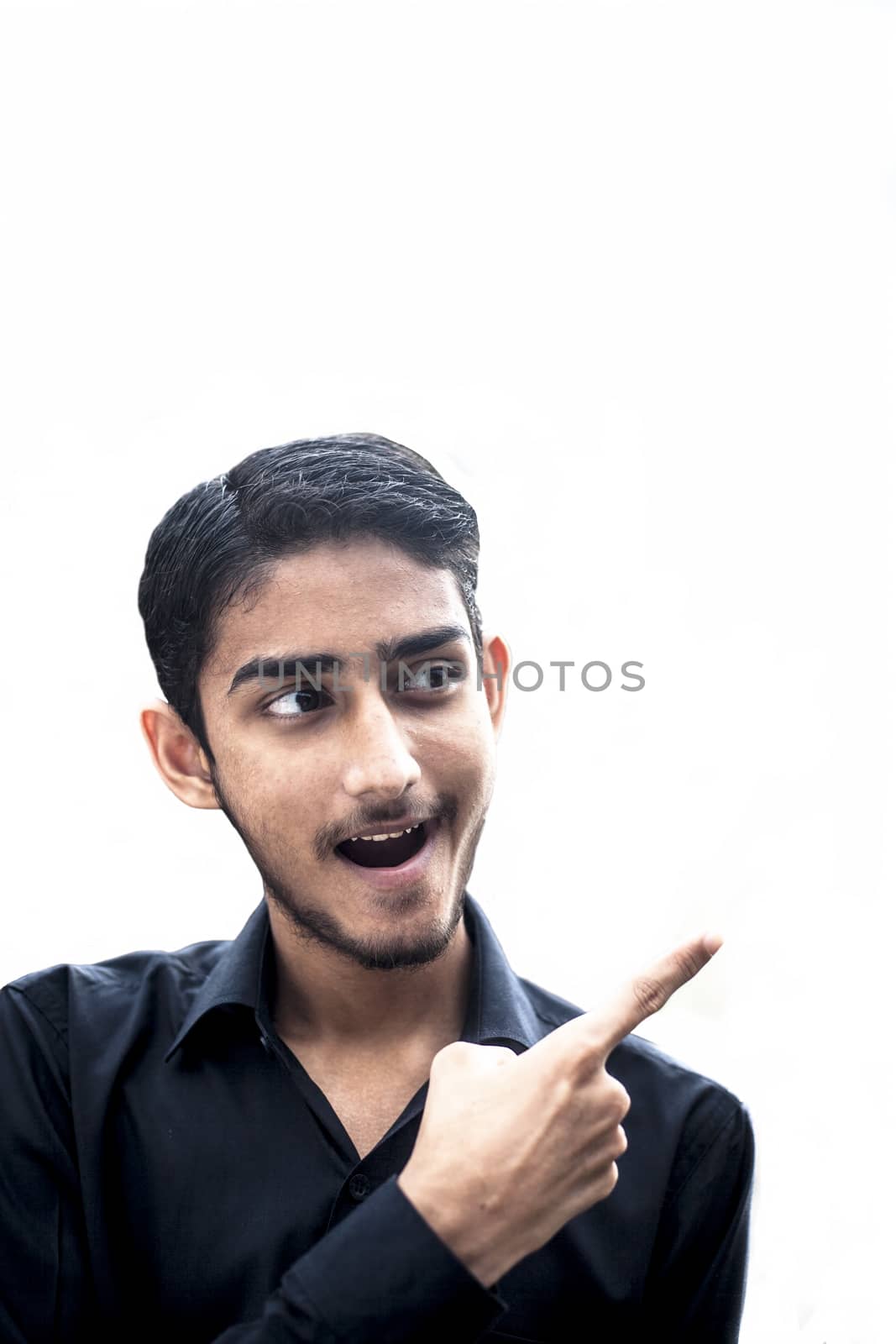 Close up of young Caucasian man with bear isolated opens mouth widely and stares at the camera while pointing towards the blank side. by mirzamlk
