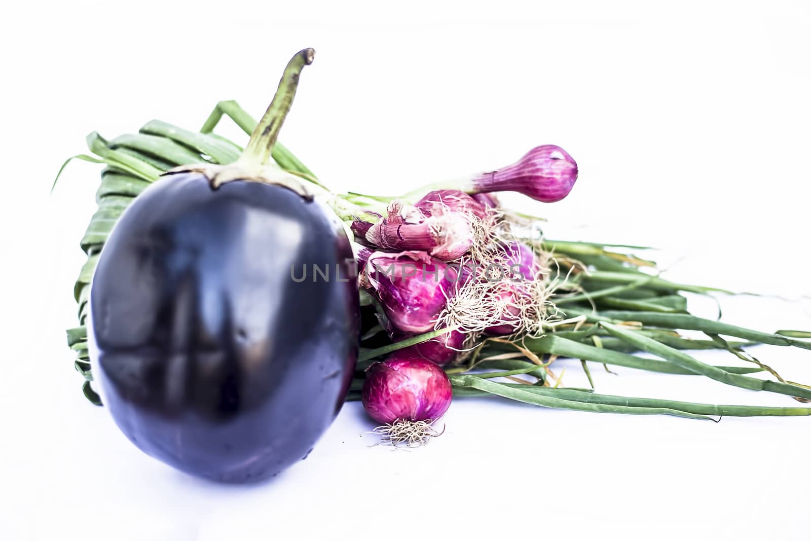 Close up of eggplant and fresh spring onion isolated on white.