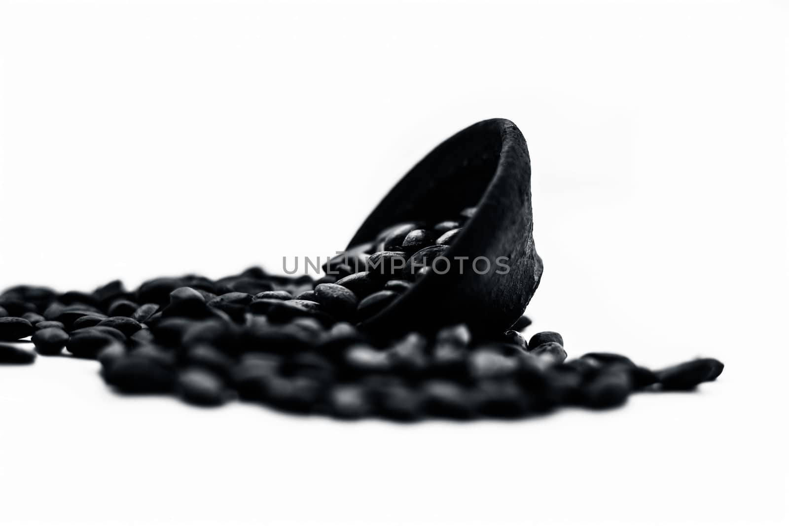 Close up of brown colored dried custard apples or sitaphal or sugar apple seeds in a black colored clay bowl isolated on white.
