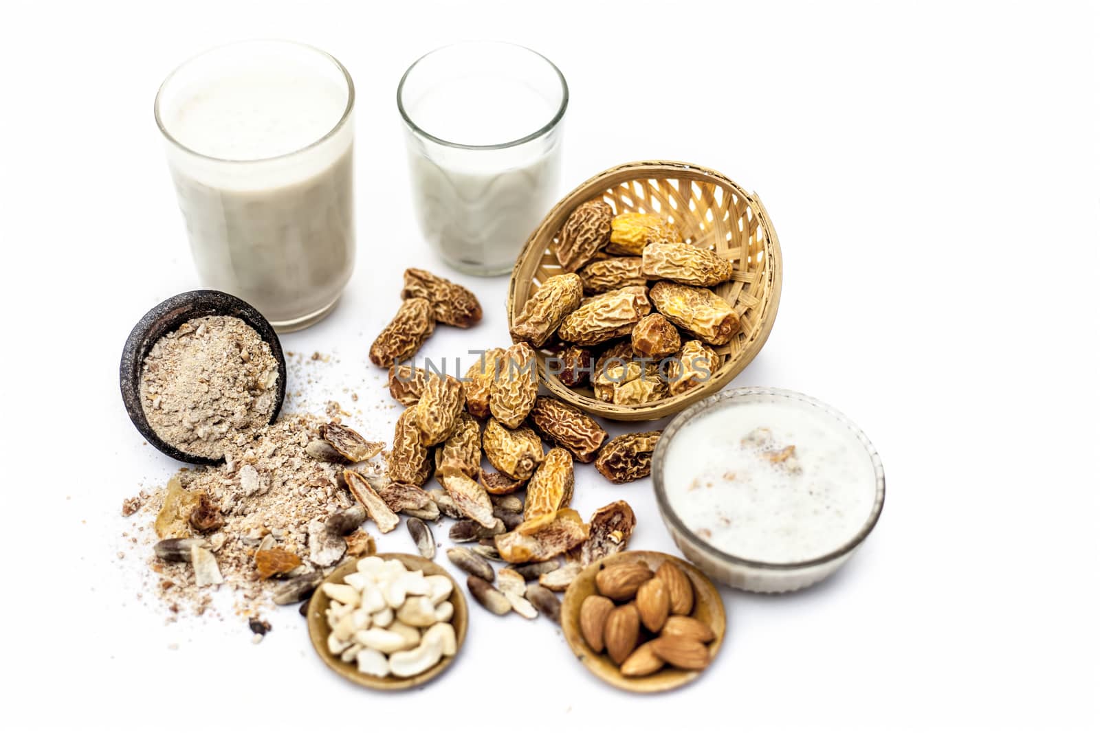 Close up of popular Indian and asian Winter drink isolated on white i.e. Kharek ka dudh or dried dates milk consisting of milk,dried dates,cashews,almonds dry fruits and sugar.