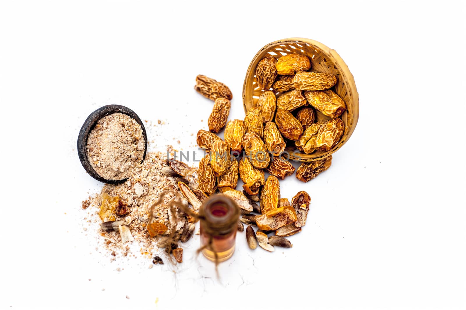 Essential oil of kharek of dried dates or sukhi khajoor or Phoenix dactylifera in a transparent glass bottle isolated on white with raw dried dates and its powder.