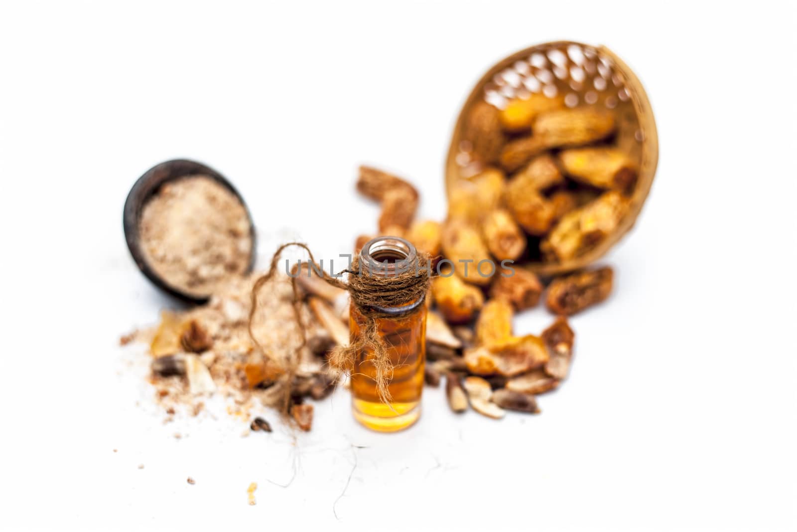 Essential oil of kharek of dried dates or sukhi khajoor or Phoenix dactylifera in a transparent glass bottle isolated on white with raw dried dates and its powder.