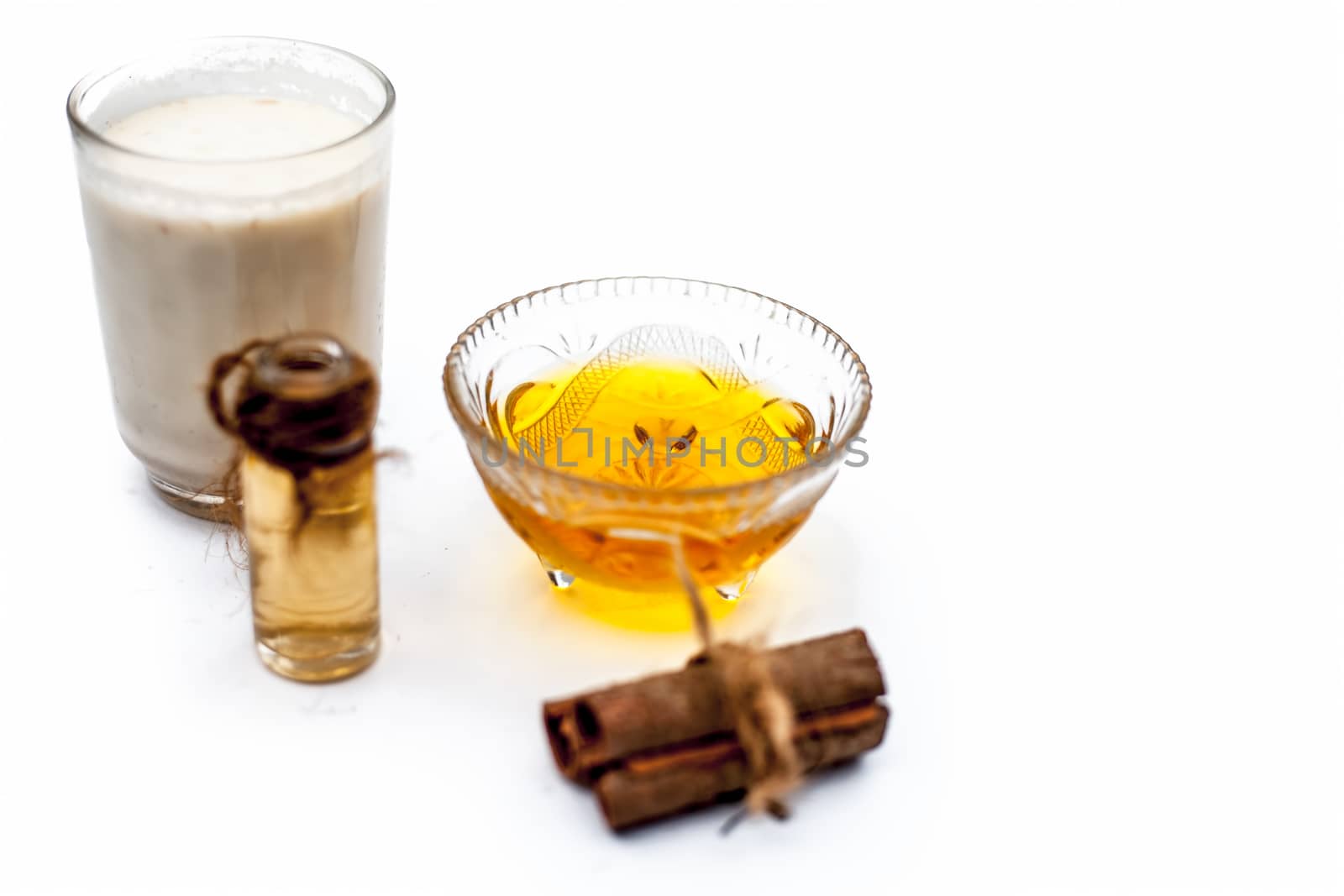 Close up of popular Indian & Asian winter drink isolated on white i.e Honey milk or shahad ka dudh in a transparent glass with entire ingredients which are milk,honey, and dry fruits.