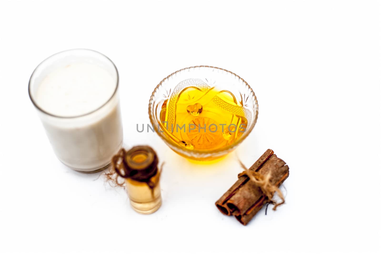 Close up of popular Indian &amp; Asian winter drink isolated on white i.e Honey milk or shahad ka dudh in a transparent glass with entire ingredients which are milk,honey, and dry fruits. by mirzamlk